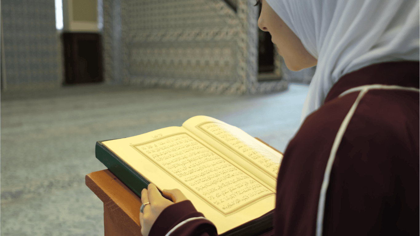 Seorang santri tahfidz putri sedang tartil membaca Al-Qur’an di dalam masjid