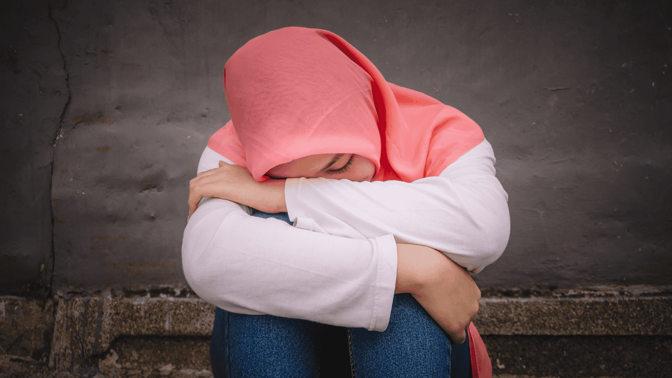 Seorang remaja muslimah berhijab tampak bersedih, menggambarkan kondisi mental health yang dapat ditenangkan dengan terapi Al-Qur’an sebagai solusi terbaik menurut riset.