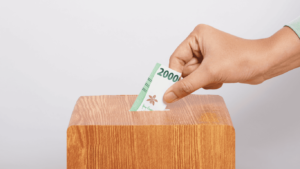 gambar tangan memasukkan uang ke dalam kotak infaq ilustrasi tujuan muamalah dalam Islam