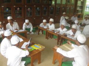 gambar beberapa laki-laki mengenakan kopiah dan bju putih sedang belajar bersama di madrasah miftahul ulum sidogiri