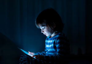 gambar anak kecil bermain gadget di ruangan gelap ilustrasi kurikulum pondok tahfidz putri yang menghadapi tantangan era digital