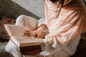 Seseorang sedang fokus membaca mushaf Al-Qur'an sebagai bagian dari penerapan tips hafalan Al-Qur'an mandiri.