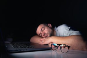 gambar pria tertidur di meja kerja contoh penyebab sulit shalat malam